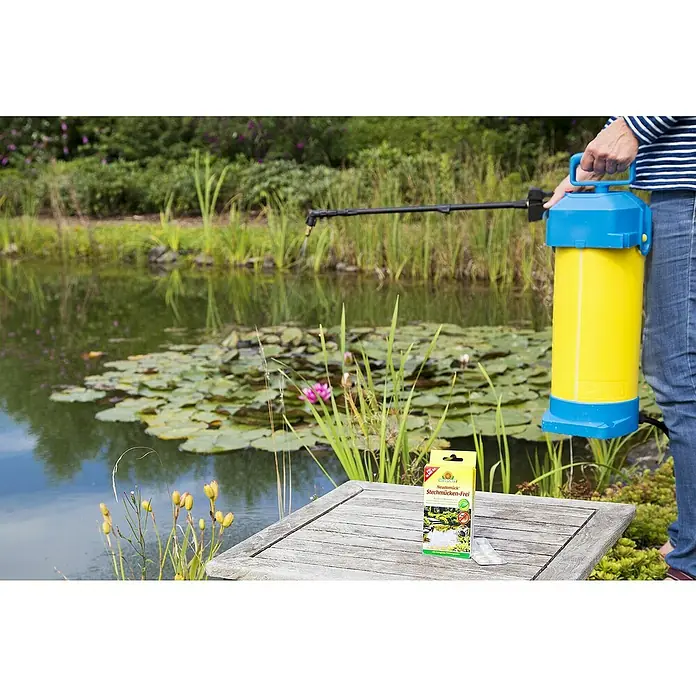 Neudorff Stechmückenfrei Neudomück - 10 Stk. - Spritzmittel gegen Stechmücken mit gelber Spritze mit blauem Kopf und Holztabletten auf einem Holztisch neben einem Teich.