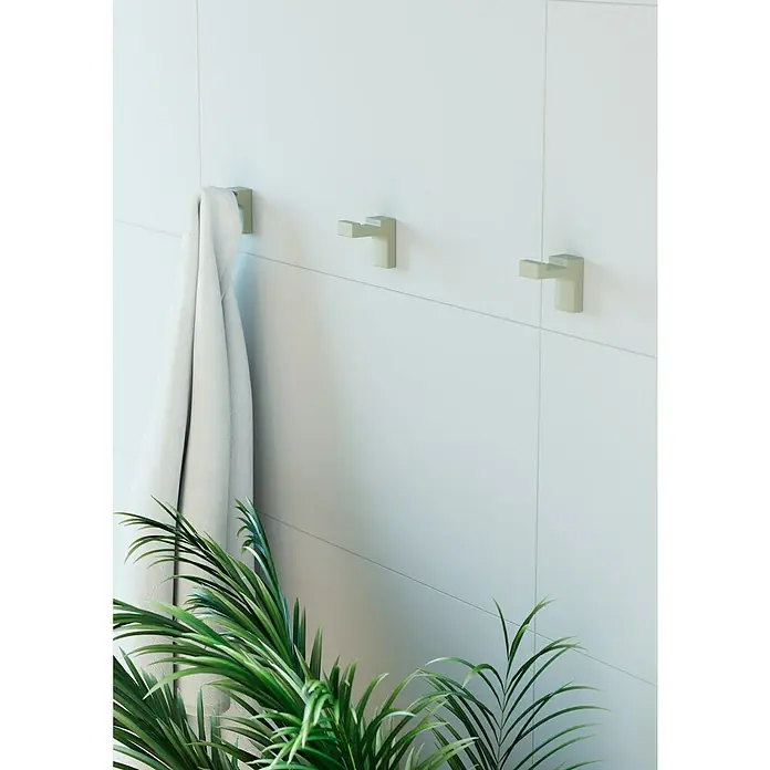 Creabath Elegance Colgador de baño - L x Al: 5,3 x 5 cm, Número de ganchos: 1 ud., Verde mist - Pared de baño luminosa con tres toalleros metálicos cuadrados y modernos, uno de ellos sosteniendo una toalla blanca. Planta decorativa en primer plano.