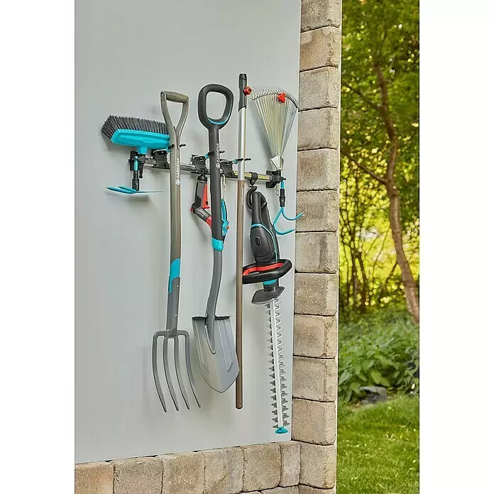 Gardena Halterung Set Einzelhalter & Einzelhaken - Traglast: 10 kg, Aluminium - Verschiedene graue und blaue Gardena Gartenwerkzeuge, darunter Besen, Forke, Spaten, Rechen und Heckenschere, ordentlich an einer Wandhalterung aufbewahrt.