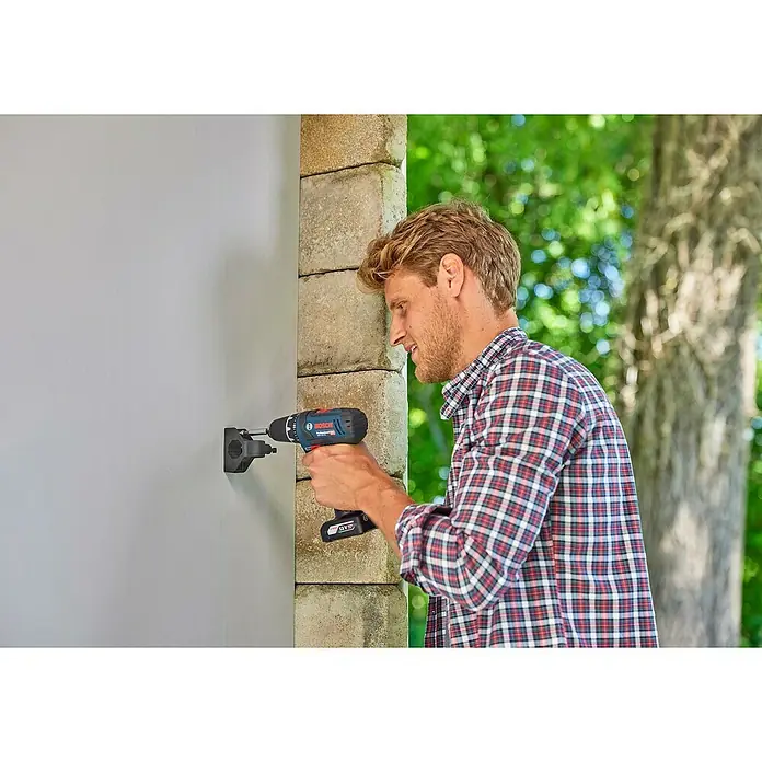 Gardena Halterung Plus - Traglast: 10 kg - Ein Mann befestigt mit einem Bosch Akkuschrauber eine Halterung an einer Wand. Der Schrauber ist blau und schwarz, und die Halterung ist schwarz.
