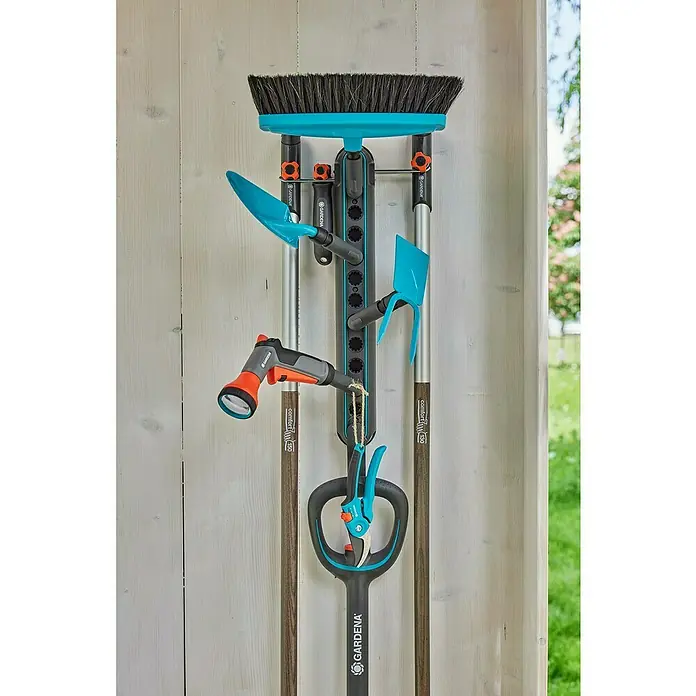 Gardena Halterung Einzelstecker Flex - Passend für: GARDENA combisystem, das Original GARDENA System & Scheren - Gartenwerkzeuge, wie Besen, Schaufel und Gartenschere, sind ordentlich an einer Gardena Gerätehalterung an einer Holzwand befestigt.