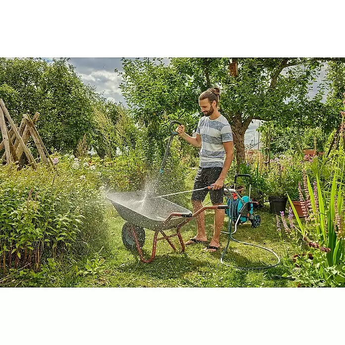Gardena Gartenschlauch Liano Xtreme Set mit Aufbewahrungstasche - 15 m, Schlauchdurchmesser: 13 mm - Mann reinigt eine Schubkarre im Garten mit Gardena Schlauchwagen und Sprühdüse.