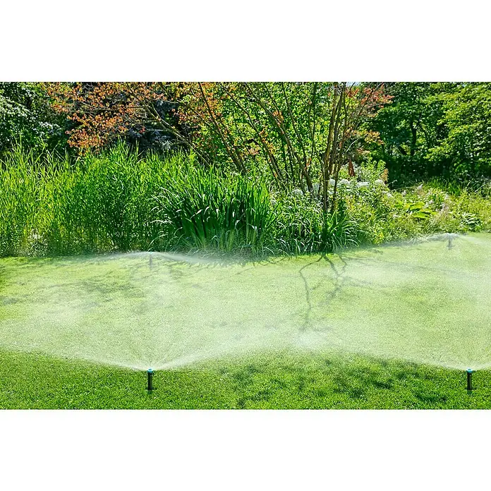 Gardena Sprinklersystem Aspersor emergente SD30 - Superficie de rociador máx.: 30 m², Riego de césped - Un aspersor de césped riega un césped verde y exuberante rodeado de un jardín con árboles y arbustos.