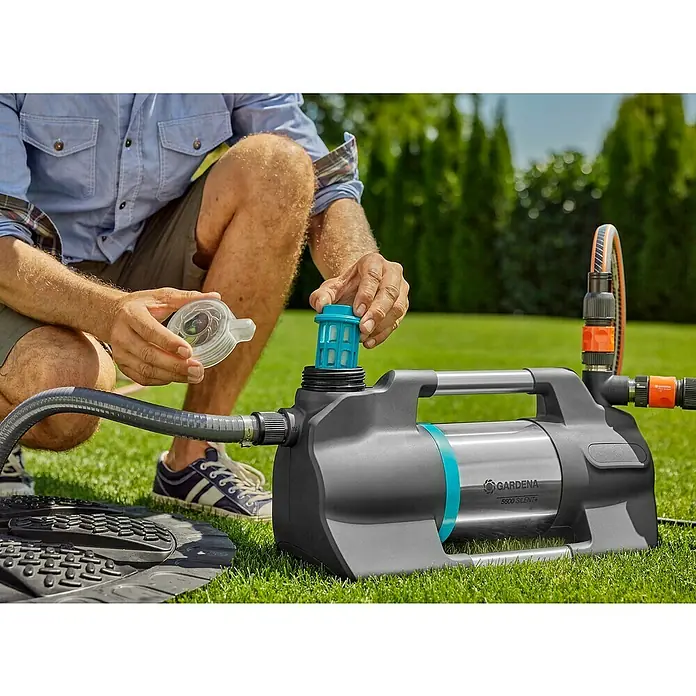 Gardena Gartenpumpe 5600 Silent+ - 900 W, Max. Fördermenge: 5.600 l/h - Eine Person montiert eine Gardena 5500 Silent+ Gartenpumpe auf einem Rasen. Der Fokus liegt auf der Installation des Filters.