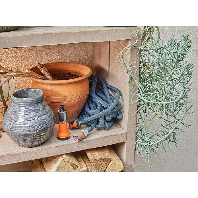 Gardena Gartenschlauch Liano Xtreme Set mit Schlauchhalter - Länge: 10 m, Schlauchdurchmesser: 13 mm - Nahaufnahme eines Gardena-Gartenschlauchs auf einem Regal mit Tontopf und blauer Vase, ideal für die Gartenbewässerung.