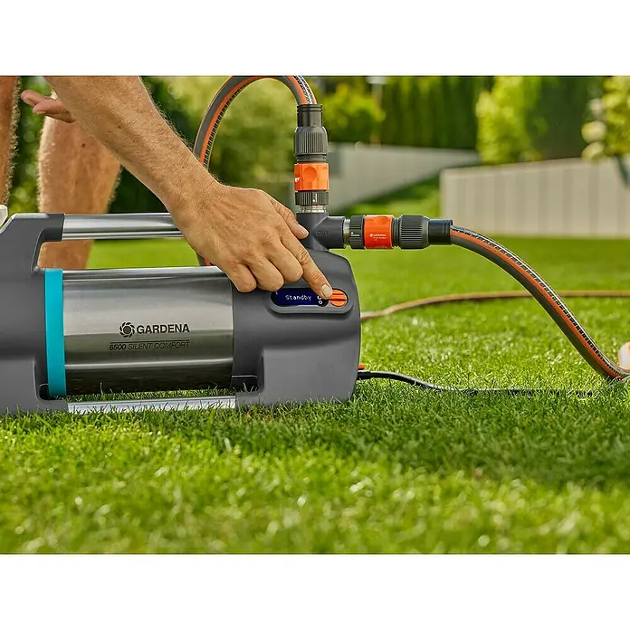 Gardena Gartenpumpe 6500 SilentComfort1.300 W, Max. Fördermenge: 6.500 l/h - Nahaufnahme einer GARDENA 6500 Silent Comfort Gartenpumpe im Einsatz auf Rasen, bedient von einer Hand.