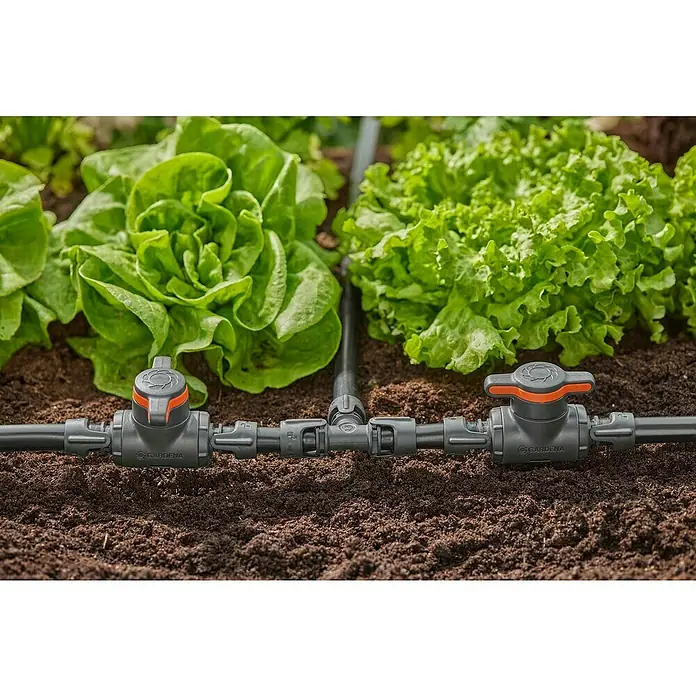Gardena Micro-Drip Válvula de regulación 13 mm (1/2") - 13 mm, Plástico - Primer plano de un sistema de microgoteo Gardena irrigando lechugas en un jardín, centrado en la distribución precisa del agua.