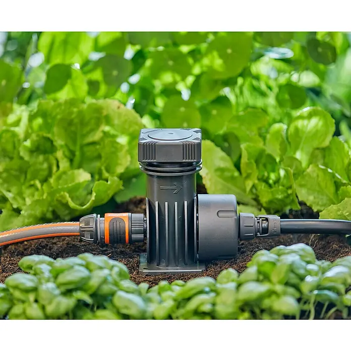 Gardena Micro-Drip Hahnanschlussstück - 1/2" x 13 mm - Bewässerungssystem-Komponentenansicht. Das System ist mit einem Schlauch verbunden und wird zum Bewässern von Pflanzen verwendet.