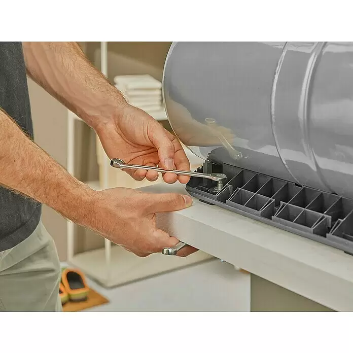 Gardena Hauswasserwerk 5600 Silent Comfort - 650 W, Max. Fördermenge: 5.600 l/h, Max. Druck: 4,7 bar - Hände ziehen eine Schraube an der Basis eines grauen Kunststoff-Außenbehälters mit einem Schraubenschlüssel fest, während der Montage.
