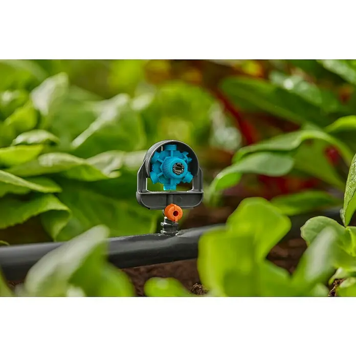Gardena Micro-Drip Sprühdüse 6 in 1 - Durchmesser Anschluss: 13 mm, Quick & Easy-Verbindungstechnik - Nahaufnahme einer Bewässerungsanlage von Gardena, die zwischen grünen Pflanzen steht. Ideal für die Gartenbewässerung.