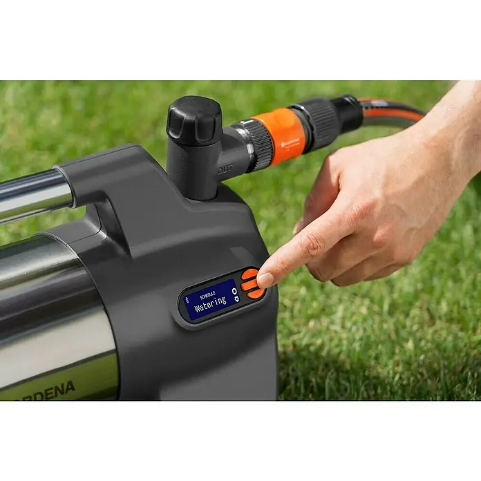 Gardena Gartenpumpe 6300 SilentComfort - 1.050 W, Max. Fördermenge: 6.300 l/h, Max. Förderhöhe: 49 m - Nahaufnahme einer Gardena-Bewässerungspumpe mit einer Hand, die eine Taste berührt, um die Bewässerung zu planen.