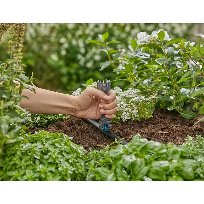 Gardena Micro-Drip Vorstecher - Passend für: Gardena Micro-Drip Artikel & Lochung des Verlegerohres, Kunststoff, Schwarz - Bild einer Hand, die ein Gardena Micro-Drip-System Werkzeug an einem Bewässerungsschlauch in einem Garten bedient.
