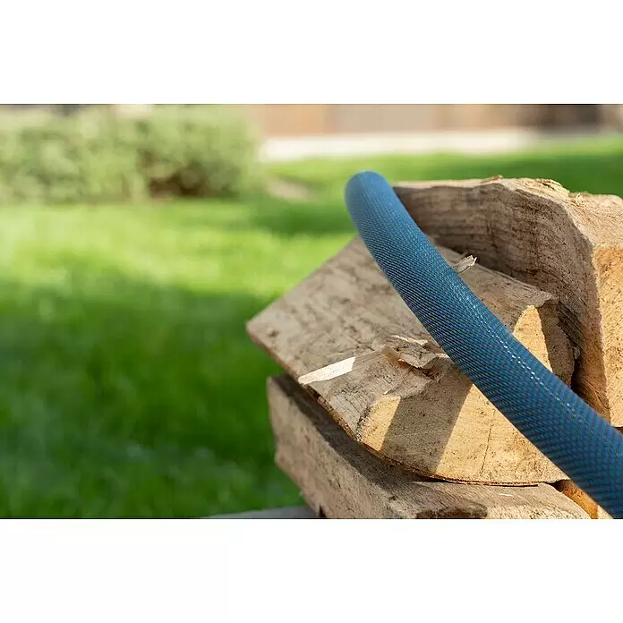 Gardena Gartenschlauch Liano Xtreme Set - 30 m, Schlauchdurchmesser: 19 mm - Blauer strukturierter Schlauch liegt auf einem Stapel Holzscheite.