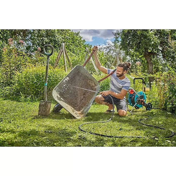 Gardena Gartenschlauch Liano Life Set - 15 m, Schlauchdurchmesser: 13 mm - Mann reinigt eine schmutzige Schubkarre mit Gardena Schlauch und Schlauchwagen auf sonnigem Rasen.