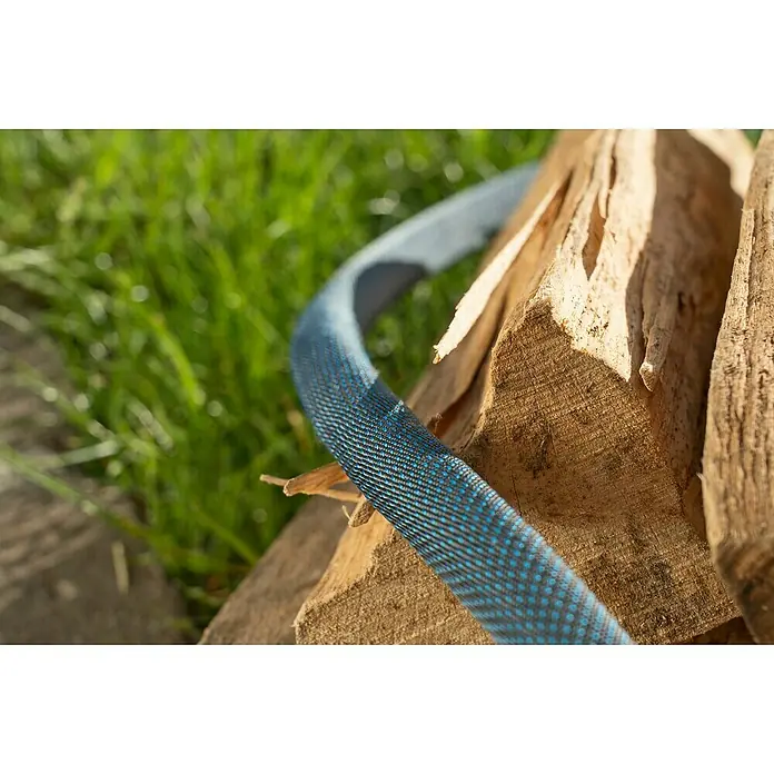 Gardena Gartenschlauch Liano Xtreme Set mit Wandschlauchhalter - Länge: 15 m - Nahaufnahme eines blauen, strukturierten Gartenschlauchs, der über Holzscheite verläuft, mit grünem Gras im Hintergrund.