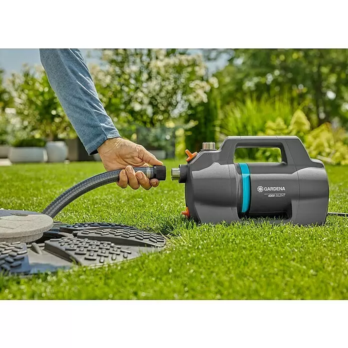 Gardena Gartenpumpe 4300 Silent - 650 W, Max. Fördermenge: 4.300 l/h - Eine Hand verbindet einen Schlauch mit einer dunkelgrauen GARDENA 4300 SILENT Pumpe mit blauen Details.