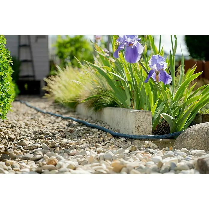 Gardena Gartenschlauch Liano Xtreme Set - 20 m, Schlauchdurchmesser: 19 mm - Gartenweg mit Kies, blauem Schlauch und blühenden Schwertlilien. Der Schlauch schlängelt sich durch den Garten.