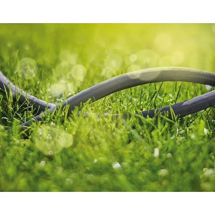 Gardena Gartenschlauch Liano Life Set - 10 m, Schlauchdurchmesser: 13 mm - Nahaufnahme eines strukturierten Gartenschlauchs, der auf einem Rasen liegt, eingefangen in weichem, natürlichem Licht, das die Textur hervorhebt.