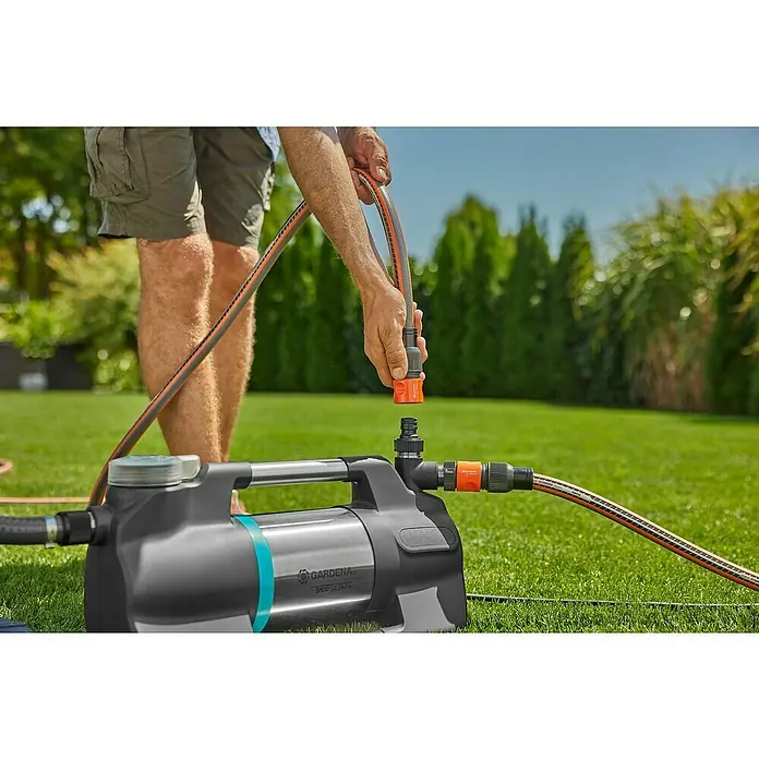 Gardena Gartenpumpe 5600 Silent+ - 900 W, Max. Fördermenge: 5.600 l/h - Der Mann schließt die GARDENA Gartenpumpe 5600 Silent an einen Gartenschlauch an, um den Garten zu bewässern.
