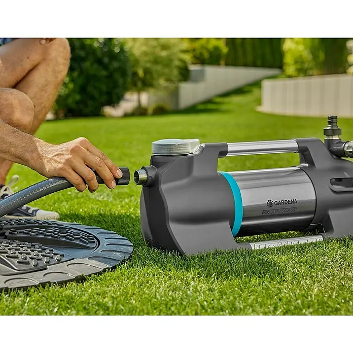 Gardena Gartenpumpe 6500 SilentComfort1.300 W, Max. Fördermenge: 6.500 l/h - Der Mann schliesst eine graue Schlauch an eine Gardena 6500 Silent Comfort Gartenpumpe auf einem Rasen an.
