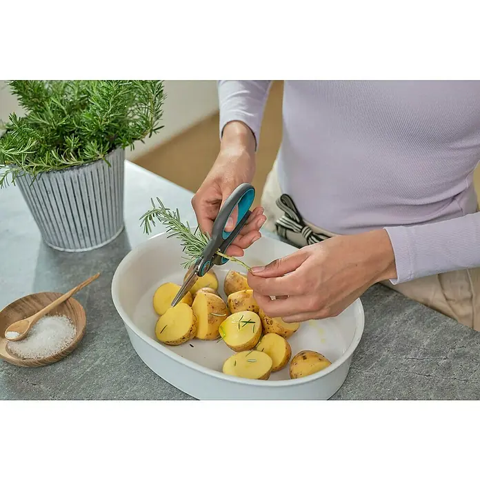 Gardena Schere HerbCut mit Holter - Geeignet für: Kräuter - Eine Person schneidet mit einer GARDENA Schere frischen Rosmarin über einer Schale mit Kartoffelscheiben.