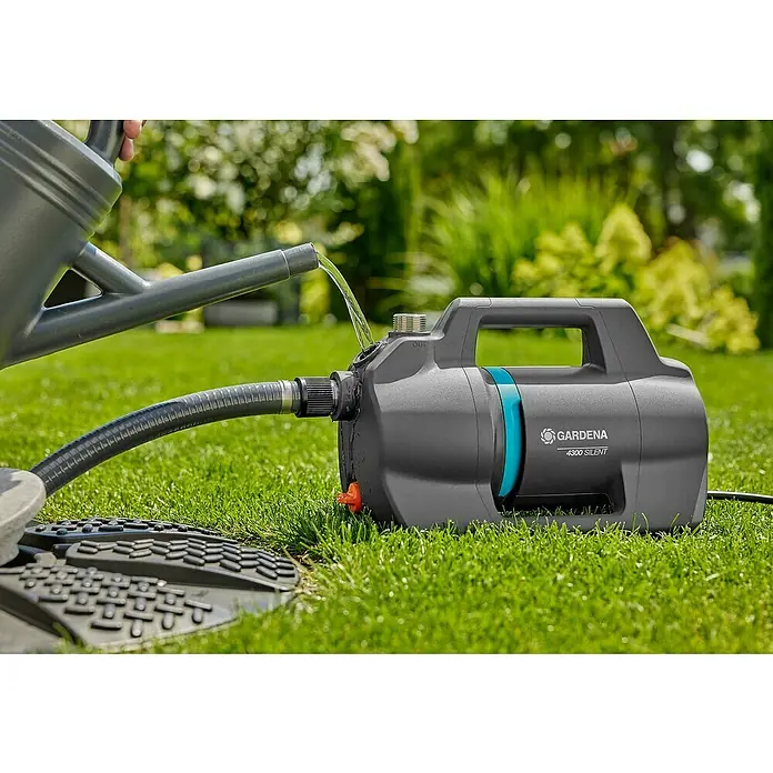 Gardena Gartenpumpe 4300 Silent - 650 W, Max. Fördermenge: 4.300 l/h - Nahaufnahme einer GARDENA 4300 Silent Gartenpumpe beim Befüllen mit Wasser aus einer Gießkanne im Garten.