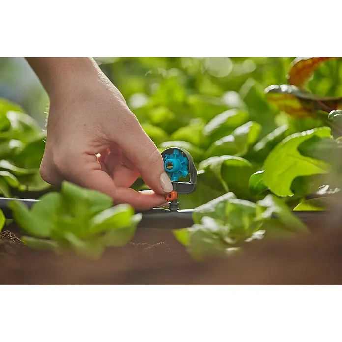 Gardena Micro-Drip Tobera pulverizadora - Diámetro conexión: 13 mm, Técnica de unión Quick & Easy - Primer plano de una mano que conecta una válvula de control Gardena Micro-Drip-System a una línea de goteo en un jardín.