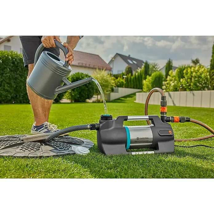 Gardena Gartenpumpe 6300 SilentComfort - 1.050 W, Max. Fördermenge: 6.300 l/h, Max. Förderhöhe: 49 m - Ein Mann gießt Wasser aus einer Gießkanne in eine GARDENA 6300 Silent Comfort Gartenpumpe auf einem Rasen im Garten.