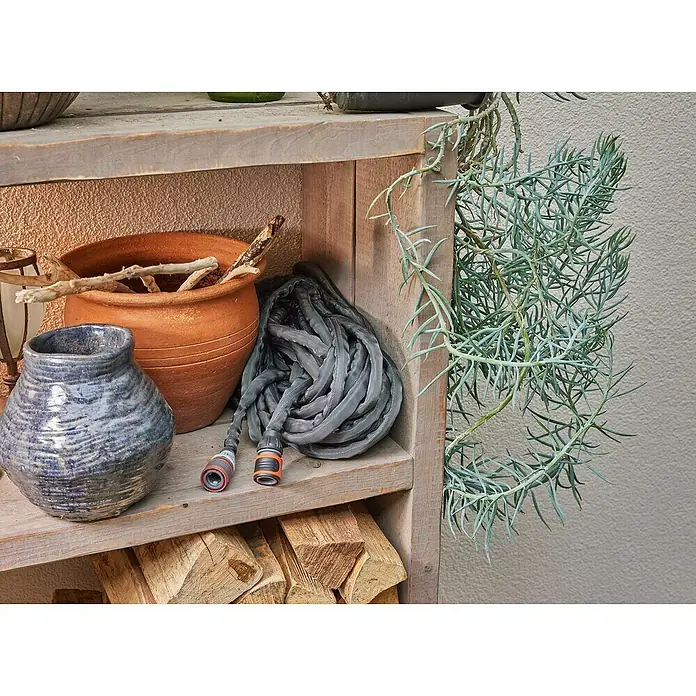 Gardena Gartenschlauch Liano Life Set - 30 m, Schlauchdurchmesser: 13 mm - Nahaufnahme eines Regals mit Töpfen, einem Gartenschlauch und Holzscheiten, ideal für Gartendekoration und Bewässerungslösungen.