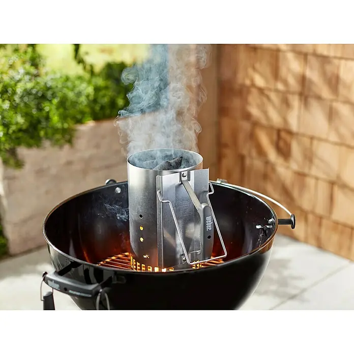 Weber Anzündkamin Rapidfire - Ø x H: 19 x 30 cm - Ein Weber Grillanzünder auf einem Holzkohlegrill, der beim Anzünden der Kohlen Rauch erzeugt. Der Anzünder steht im Grill.