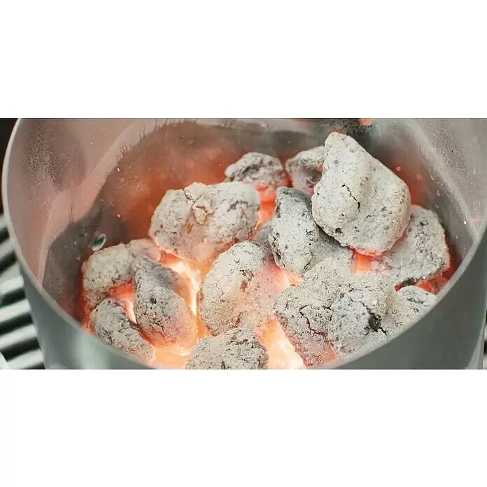 Weber Anzündkamin Rapidfire - Ø x H: 19 x 30 cm - Mit weißer Asche bedeckte Holzkohlebriketts glühen orangefarben in einem grauen Metall-Anzündkamin.