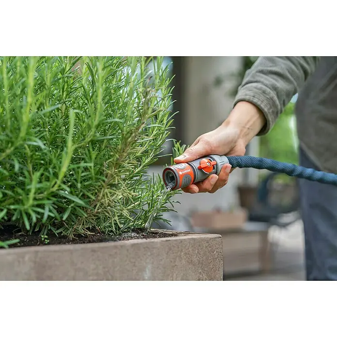 Gardena Gartenschlauch Liano Xtreme Set mit Hahnverbinder - Schlauch, Bewässerungsbrause, Indoor-Schlauchverbinder mit Regulierventil, Wasserstop, Hahnverbinder - Bewässerung einer Pflanze mit einem Gardena-Bewässerungssystem. Das System besteht aus einem Schlauch und einem Sprühkopf.