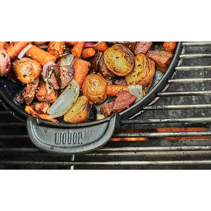 Weber Gourmet BBQ System Plancha - Diámetro: 38,6 cm, Hierro fundido esmaltado - Verduras asadas preparadas en una sartén para parrilla Weber sobre una parrilla. La sartén tiene el logo de Weber.