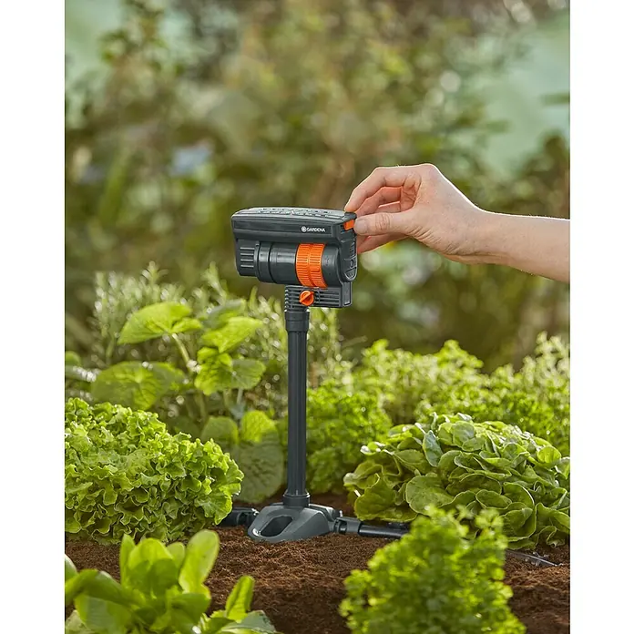 Gardena Micro-Drip Tubo prolongador para OS 90 - 2 ud., Largo: 20 cm - Primer plano de un control de riego GARDENA Micro-Drip-System en el jardín, operado por una mano.