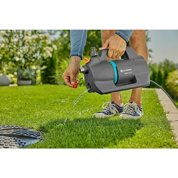 Gardena Gartenpumpen-Set 4200 Silent600 W, Max. Fördermenge: 4.200 l/h - Die Gardena 4200 Silent Hauswasserautomat pumpt Wasser auf einem Rasen ab, wobei die Leistung und das ruhige Design hervorgehoben werden.