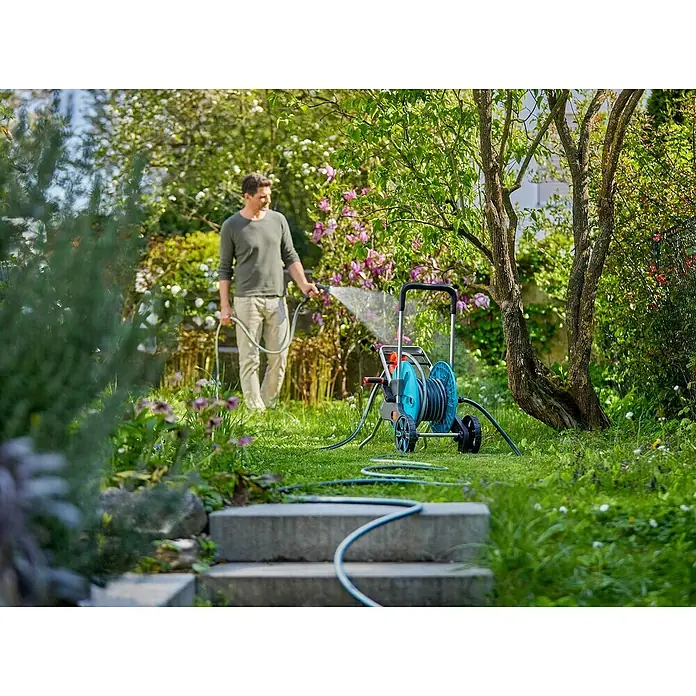 Gardena EcoLine Gartenschlauch - 20 m - Ein Mann bewässert seinen Garten mit einer Gardena Schlauchtrommel. Das System ist mobil und einfach zu bedienen.