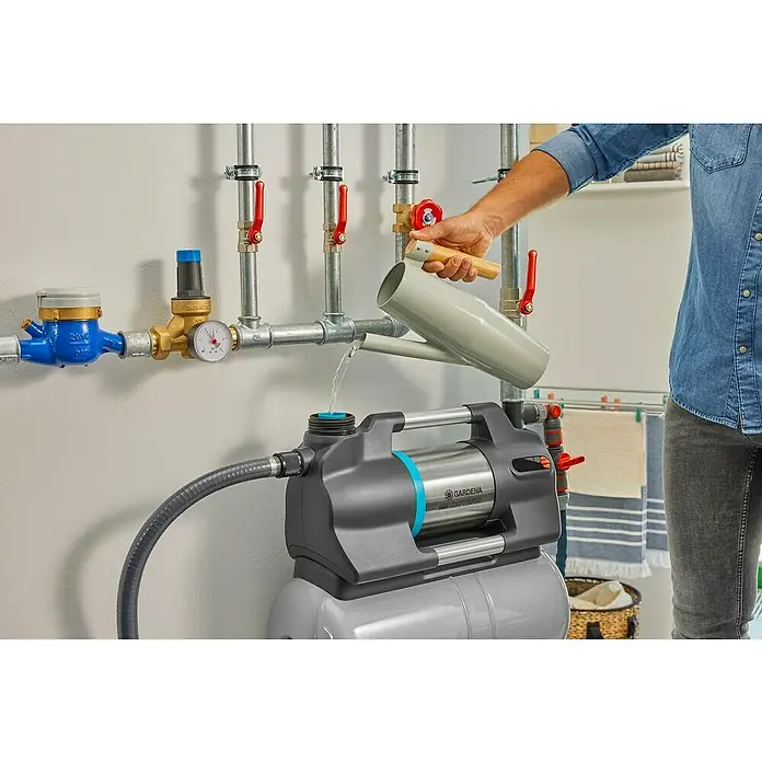 Gardena Hauswasserwerk 5600 Silent Comfort - 650 W, Max. Fördermenge: 5.600 l/h, Max. Druck: 4,7 bar - Ein Mann befüllt eine GARDENA Hauswasseranlage 5000 Silent Comfort mit einem Gießkanne, um die optimale Leistung zu gewährleisten.