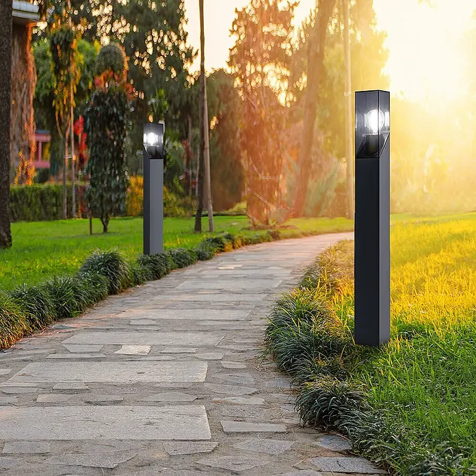 Forlight Munic Lámpara de pie para exterior - 15 W, Color del marco: Antracita, 13 x 13 x 80 cm, Sin bombillas - Un sendero pavimentado con luces exteriores modernas, creando un ambiente brillante y acogedor en el parque. La luz enfatiza el diseño.