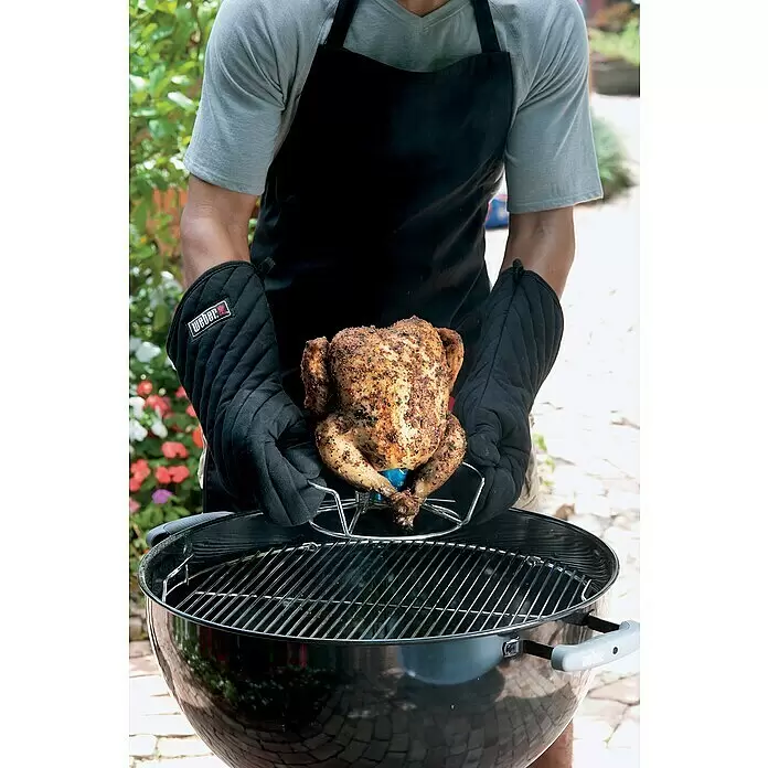 Weber Geflügelhalter - Edelstahl - Person platziert gewürztes Bierdosenhähnchen auf Ständer mit Weber Ofenhandschuhen in Weber Grill.