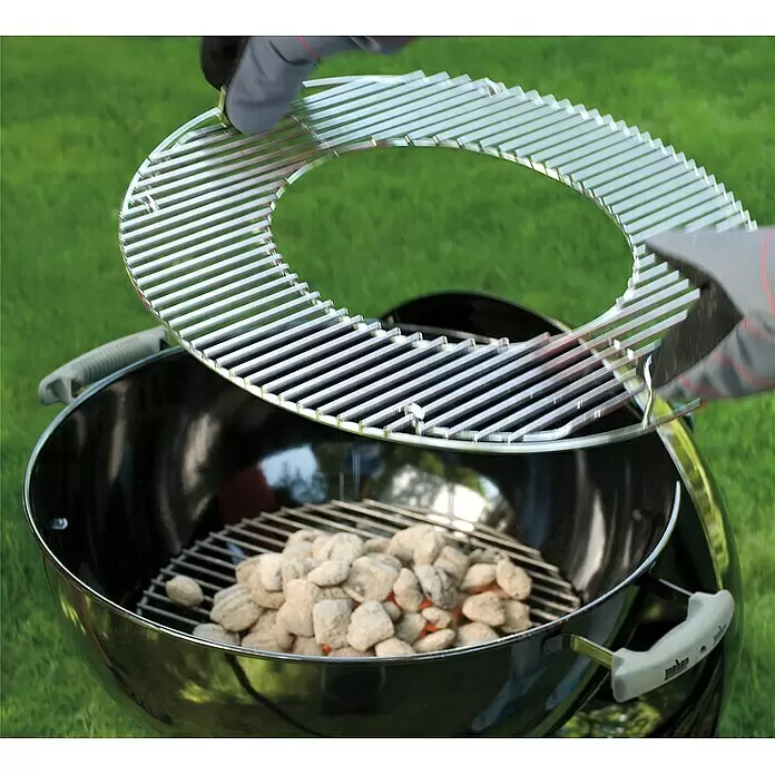 Weber Gourmet BBQ System Grillrost - L x B: 56,61 x 54,61 cm, Durchmesser: 57 cm, Verchromter Stahl - Behandschuhte Hände setzen einen silbernen Grillrost mit austauschbarem Einsatz auf glühende Kohlen in einem Kugelgrill.