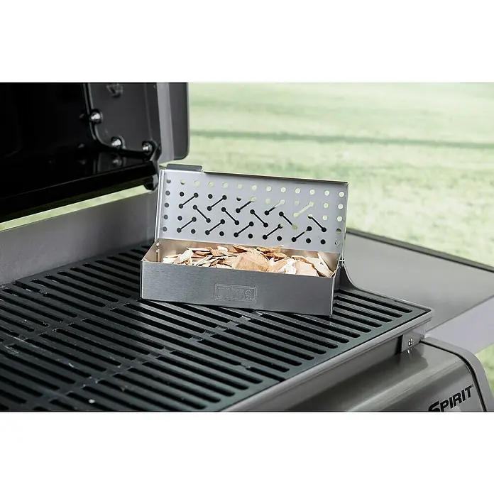 Weber Chips ahumadores - Específico para: Ahumar aves, 700 g - La caja de ahumado Weber sobre una parrilla, llena de astillas de madera, diseñada para agregar sabor ahumado a los alimentos.