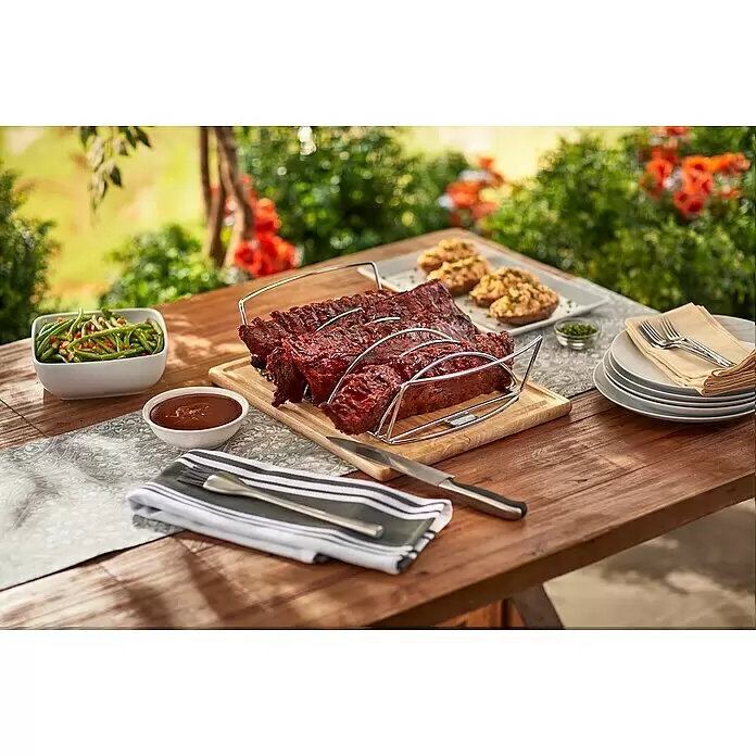 Weber Bratenkorb - L x B x H: 43,5 x 26,5 x 11 cm - Silbernes Metallgestell mit gegrillten Rippchen auf einem Holztisch, umgeben von weiteren Gerichten im Freien.