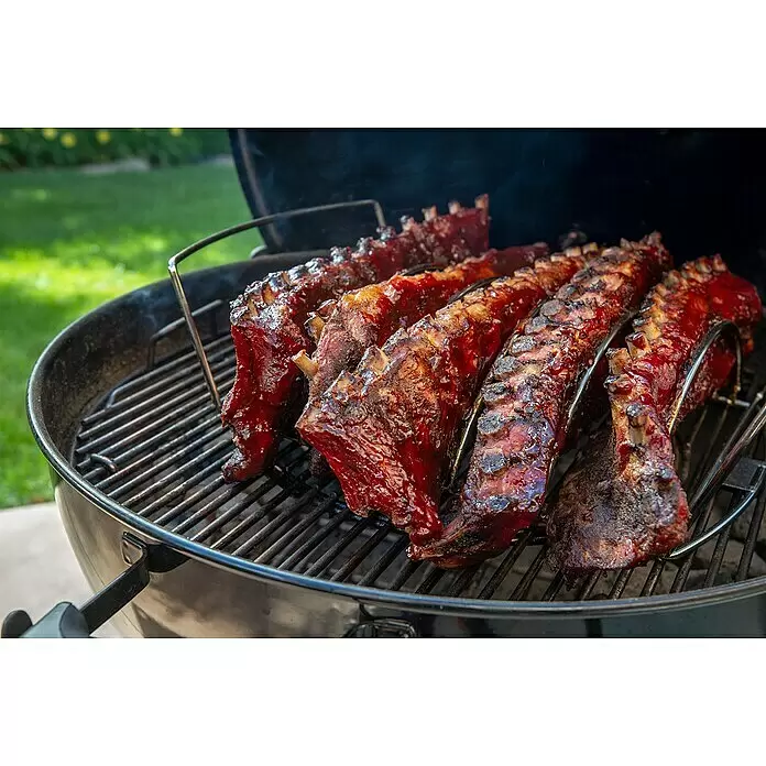 Weber Bratenkorb - L x B x H: 43,5 x 26,5 x 11 cm - Marinierte Rippchen mit glänzender BBQ-Sauce garen auf einem Holzkohlegrill, Rauch steigt auf.