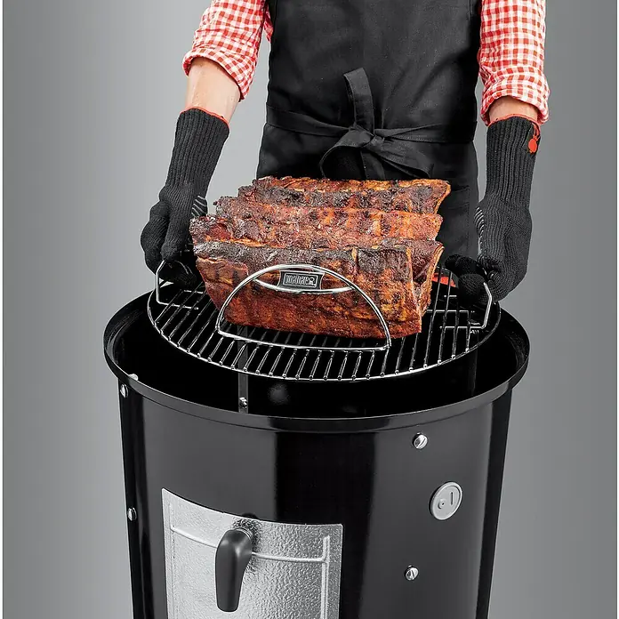 Weber Räucherofen Smokey Mountain Cooker - Durchmesser Grillfläche: 47 cm, Schwarz - Ein Mann legt mit Grillhandschuhen einen Braten auf einen Weber Smokey Mountain Cooker Smoker.