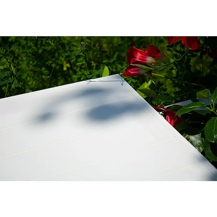 KHW Gartenbank Berlin - B x T x H: 174 x 49 x 41 cm, Weiß - Nahaufnahme einer weißen Terrassentischplatte mit feinen Rillen, umgeben von roten Blüten und üppigem Grün.
