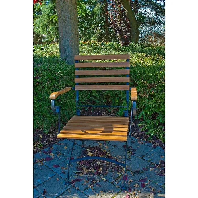 Acamp Gartenmöbel-Set Lindau - 5 -tlg., Akazie, Eisen, Braun - Eine Gartenbank aus Holz und Metall steht auf einem gepflasterten Weg, umgeben von üppigem Grün. Die Bank lädt zum Verweilen im Garten ein.
