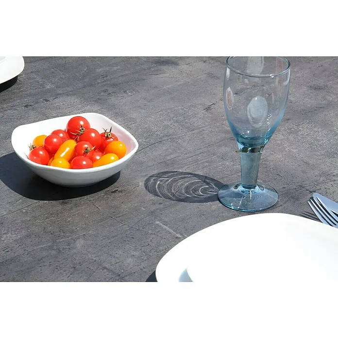Acamp Gartenmöbel-Set Urban/Extensio - 7 -tlg., Aluminium, HPL, Textil, Silber - Nahaufnahme einer Schale mit Tomaten, einem blauen Glas und Besteck auf einem Tisch, der eine elegante und sommerliche Atmosphäre schafft.