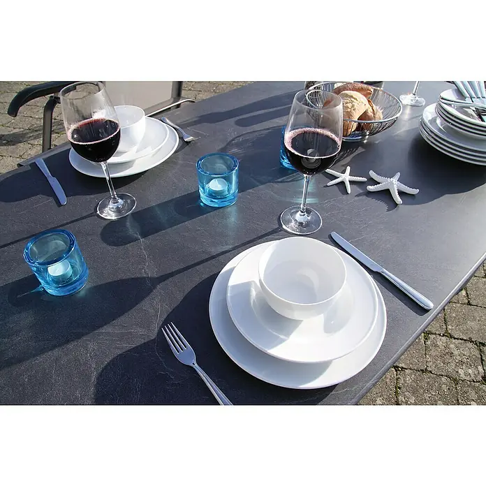 Acamp Gartenmöbel-Set Urban/Acaplan - 5 -tlg., Aluminium, Topalit, Acatex, Anthrazit, Stapelbar - Ein Esstisch mit Weingläsern, Tellern, Besteck und Dekorationen für ein stilvolles Essen im Freien.