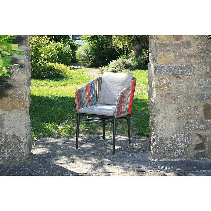 Acamp Gartensessel Manhattan Set - 6 Stk., Aluminium, Polyester, Stapelbar, Bunt, B x T x H: 63 x 50 x 81 cm - Ein moderner Outdoor-Sessel mit farbigen Akzenten und grauem Kissen, platziert in einem Steintor inmitten eines grünen Gartens.