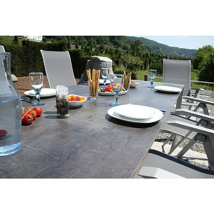 Acamp Gartenmöbel-Set Urban/Extensio - 7 -tlg., Aluminium, HPL, Textil, Silber - Ein grauer Gartentisch ist mit Speisen, Getränken und Geschirr für ein Essen im Freien gedeckt. Stühle umgeben den Tisch.